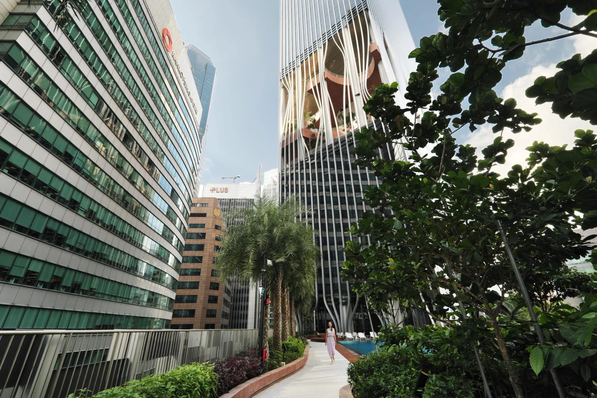 Des gratte-ciel modernes surplombent un jardin suspendu où une femme se promène au cœur de Singapour.