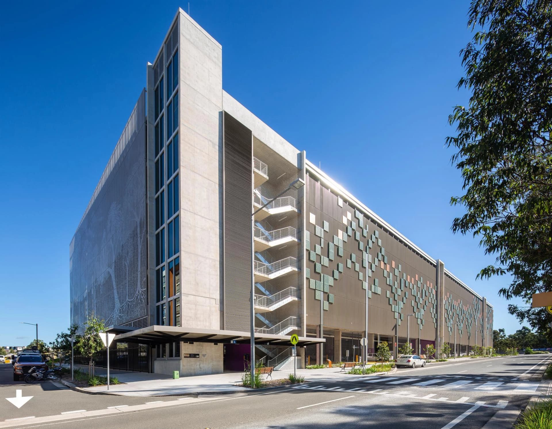 Un grand parking moderne à plusieurs étages avec une façade en béton et en métal sous un ciel bleu dégagé.
