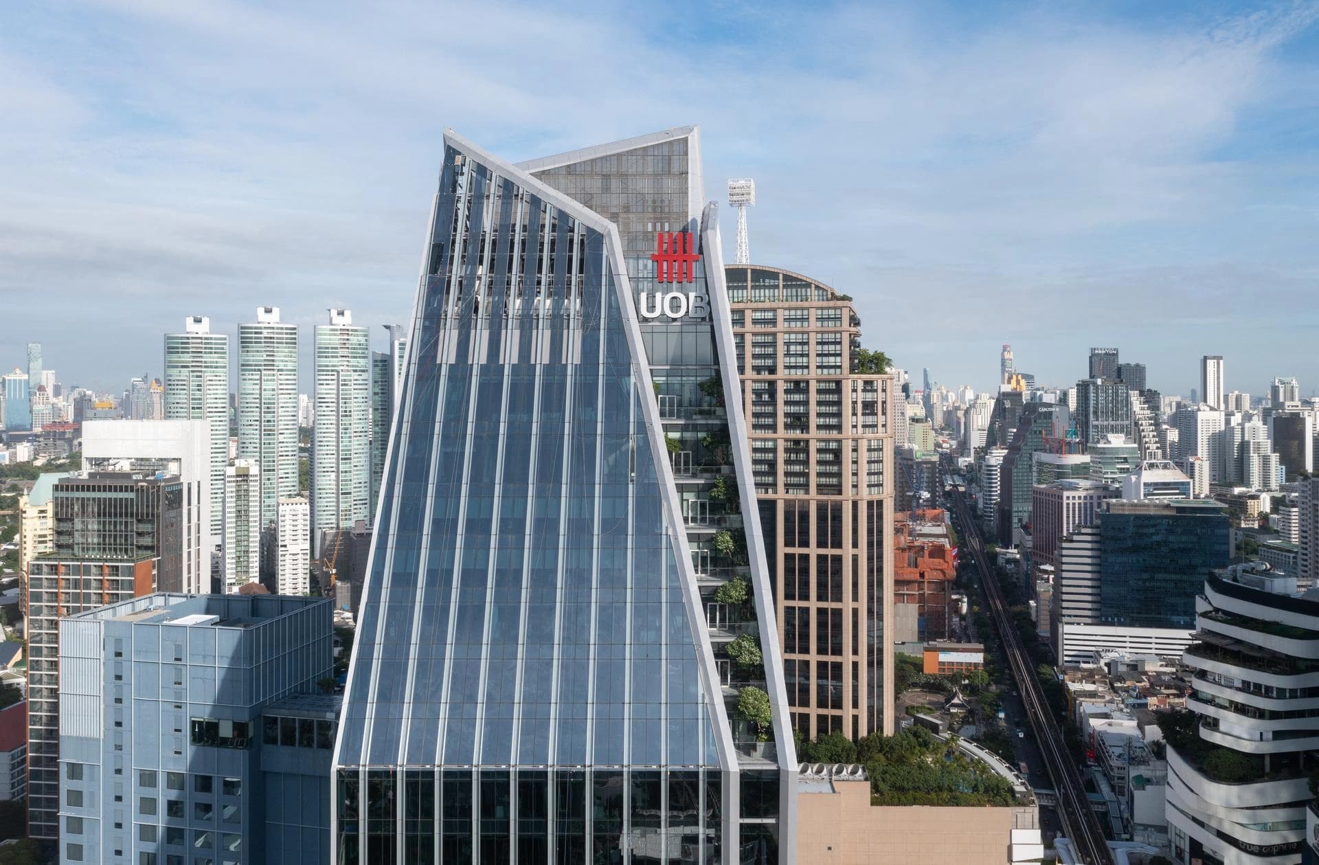 Gratte-ciel contemporain aux façades vitrées dominant une skyline urbaine dense, illustrant une architecture moderne au cœur de la ville.