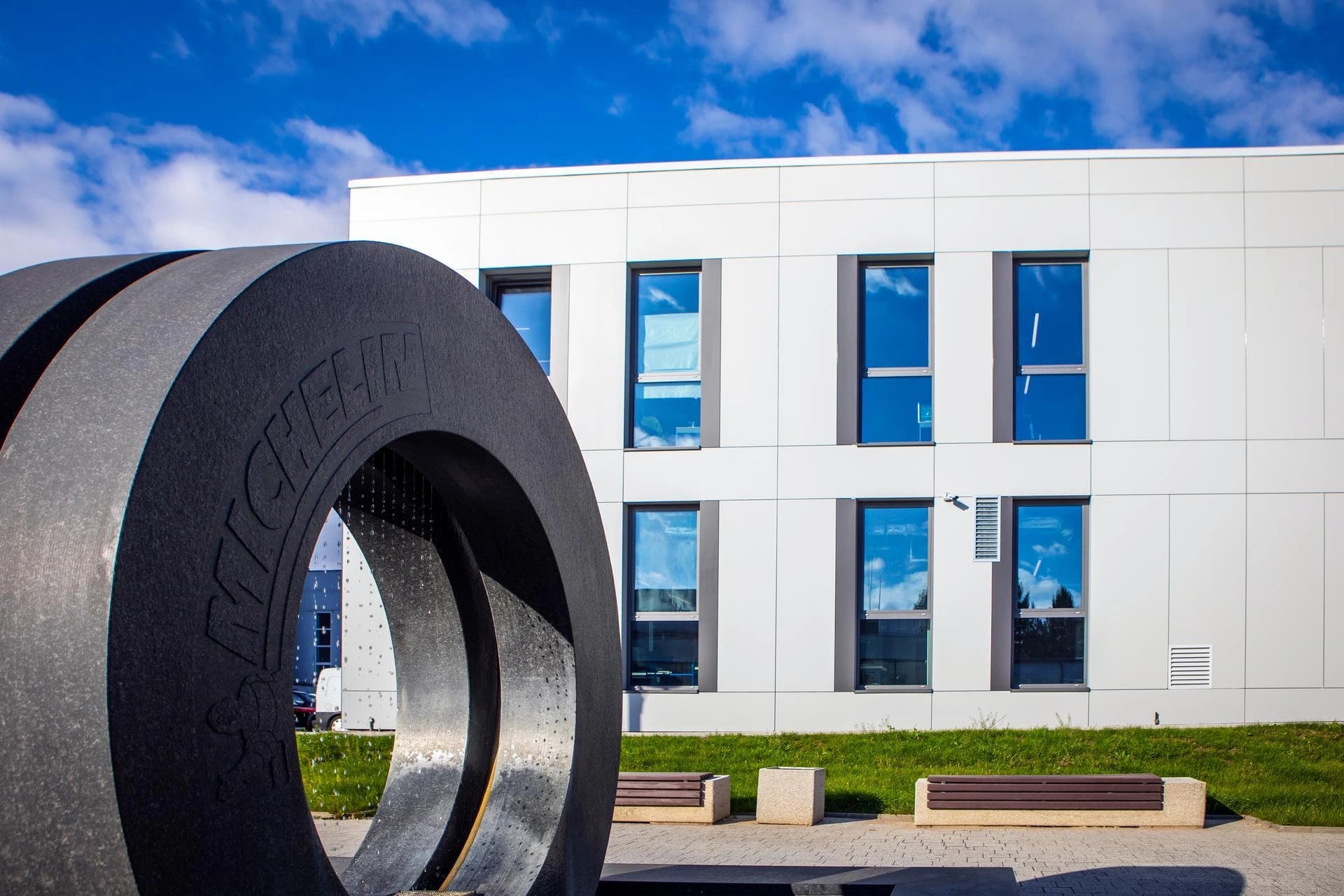 Large Michelin tire sculpture in front of a modern white office building on a sunny day.