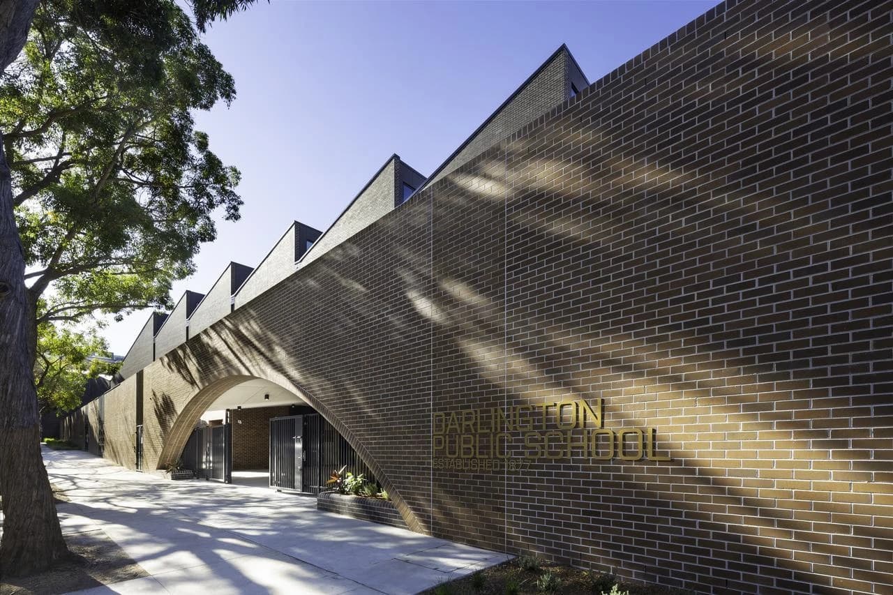 Façade moderne en briques de l'école publique Darlington, caractérisée par une grande arche d'entrée et un toit à redents.