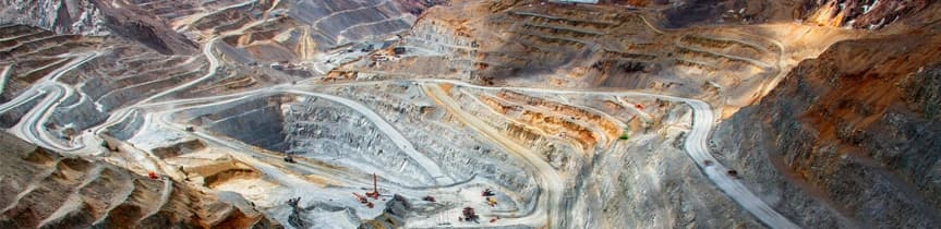 Vue panoramique d'une mine à ciel ouvert massive avec des terrasses et des routes sinueuses pour véhicules industriels.