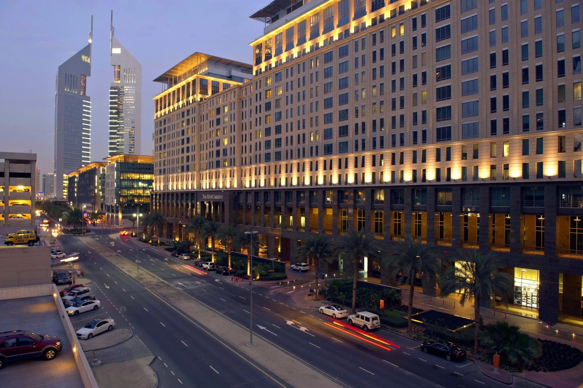 Vue au crépuscule du Ritz-Carlton et des Emirates Towers à Dubaï avec des lumières de voitures sur la rue.